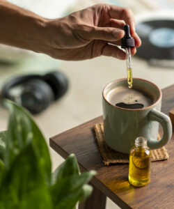 Man dropping CBD oil or Cannabis oil into a coffee cup while relaxing at home